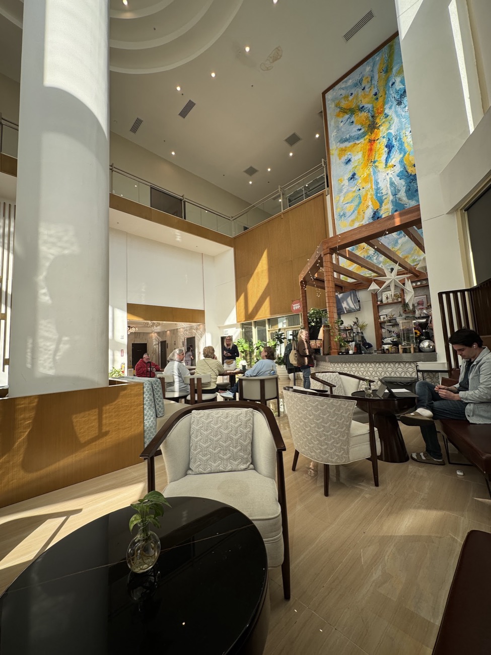 The Galaxy Hotel lobby: cream armchairs and a tall blue-and-gold mural under a bright atrium
